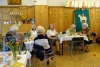 Seniorzy siedząc przy stołach wspólnie spożywają posiłek wielkanocny