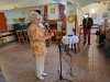 Przy statywie mikrofonu stoi seniorka, która śpiewa przed publicznością